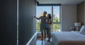 Asian couple inspecting blackout roller blinds effectiveness in a Singapore HDB bedroom by Ministry of Blind